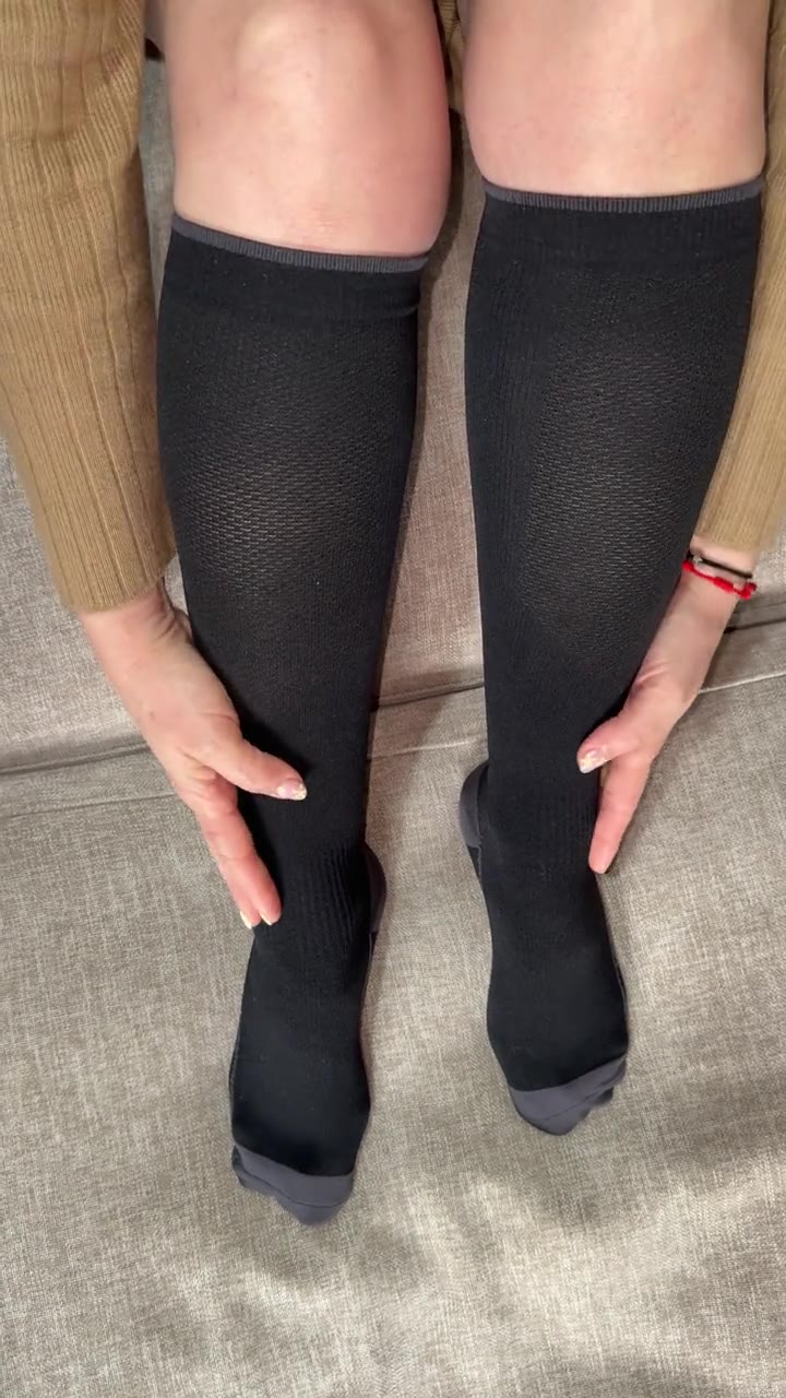 Mujer sentada con calcetines de compresión Kompresion Recovery negros, lista para un viaje largo
