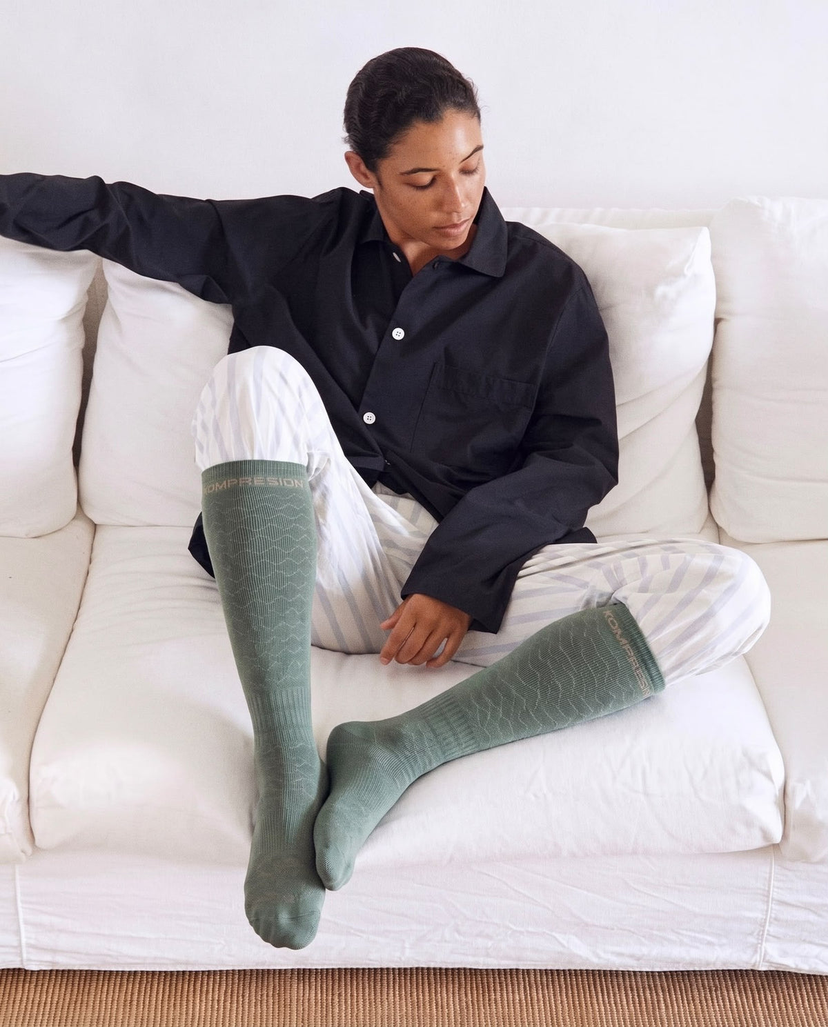Mujer descansando en el sofá con calcetines de compresión Kompresion verdes